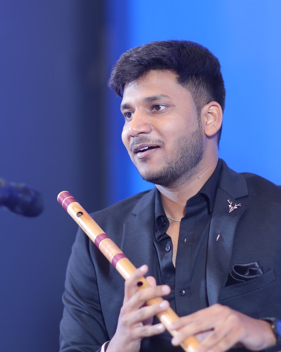 Deepanshu Jindal holding a bamboo flute on stage